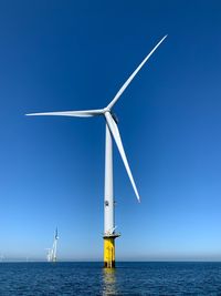 Wind turbines in sea against sky