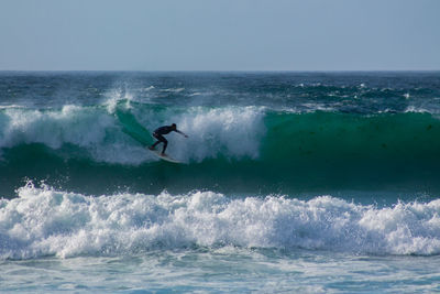 Man surfing in sea against clear sky