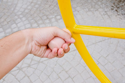 Close-up of person holding yellow hand on tiled floor