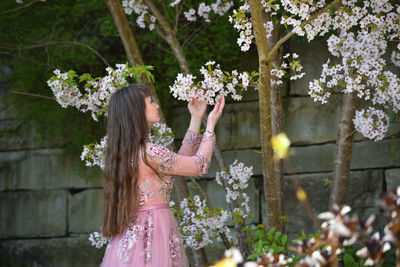 Woman standing by cherry blossom at park