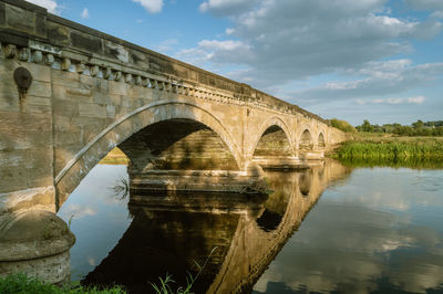 Arch bridge over river against sky
