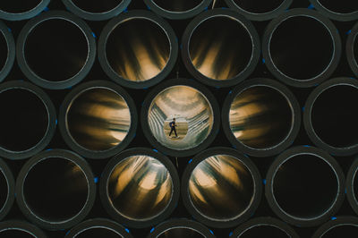 Man walking at beach seen through stacked pipes