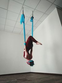 Low angle view of woman hanging on textile while exercising at home