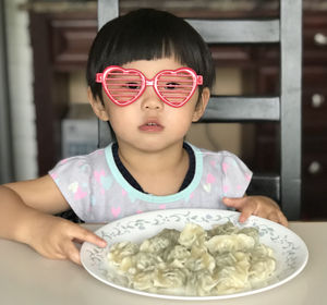 Portrait of cute girl wearing sunglasses sitting at dining table