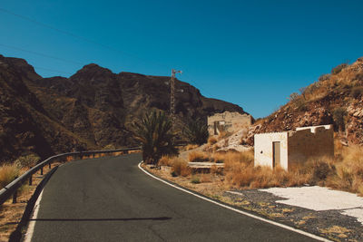 Road by mountains against clear sky