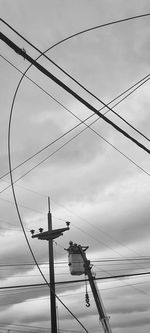 Low angle view of silhouette electricity pylon against sky