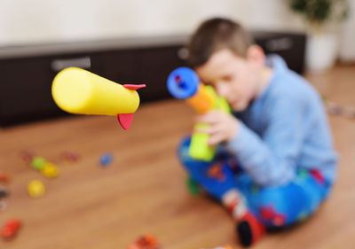 A small hyperactive child preschool boy shoots foam bullets from a toy gun weapon.