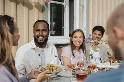 Woman serving baby potatoes to male and female friends during dinner party at cafe