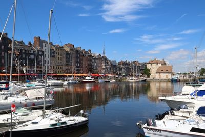 Boats moored at harbor in city against sky