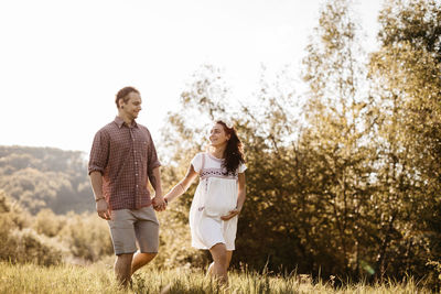 Couple walking on grassy field against clear sky at park