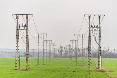 Electricity pylon on field against sky