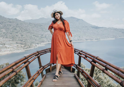 Portrait of woman standing on railing against mountain