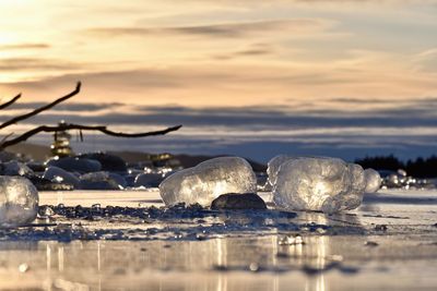 Ice floating on sea against sky during sunset