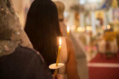 Rear view of women holding lit candles
