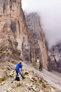 Rear view of man photographing tre cime di lavaredo at dolomites during foggy weather