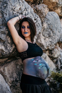 Portrait of young woman standing on rock