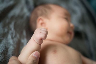 Cropped image of parent holding newborn baby hand lying on bed