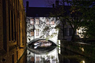 Arch bridge over canal amidst buildings in city