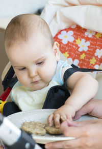 Cropped hands of parent feeding toddler daughter on bed