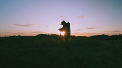 Low angle view of person on field against sky during sunset