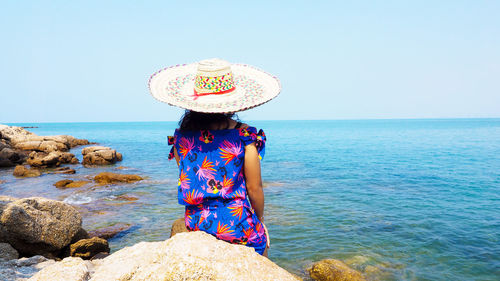 Woman wearing hat against sea against clear sky