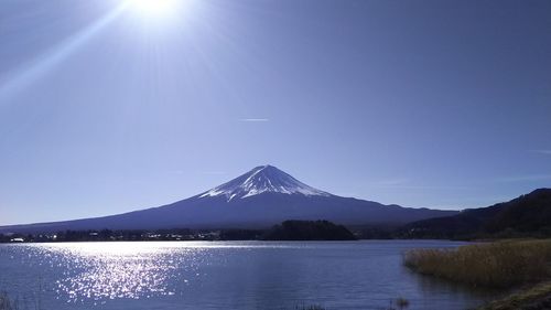 Scenic view of lake and mountains against clear blue sky