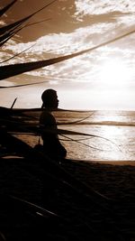 Silhouette man standing at beach against sky during sunset