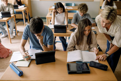 Female professor helping teenage girl while learning in school classroom