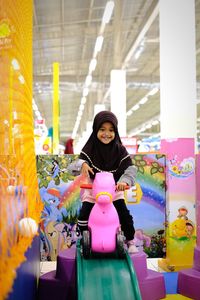 Portrait of girl wearing hijab sitting on rocking horse