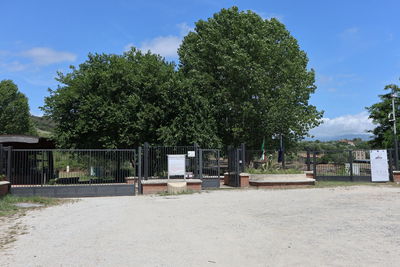 Trees and houses on field against sky