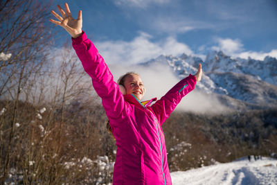 Smiling girl with arms raised standing in snow