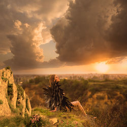 Scenic view of rocks on field against sky during sunset