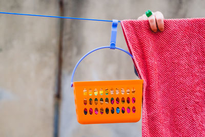 Cropped hand of woman drying towel by bucket hanging on clothesline