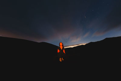 Silhouette man standing on mountain against sky during sunset