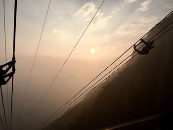 Low angle view of silhouette electricity pylon against sky