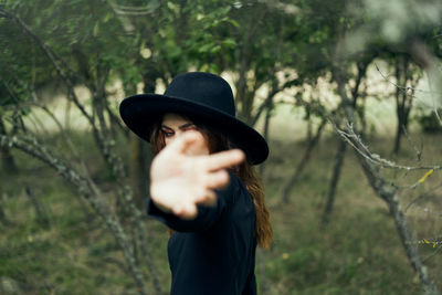 Man wearing hat standing by tree