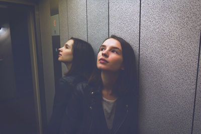 Portrait of woman standing against wall