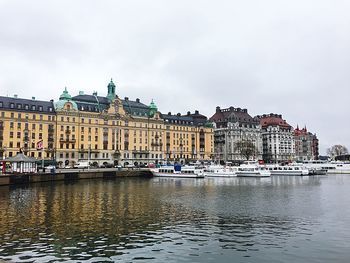 Buildings by river against sky in city