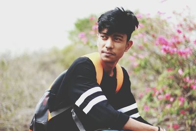 Thoughtful young man looking away while crouching on field