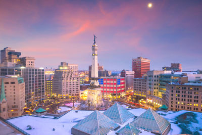 Illuminated buildings in city against sky