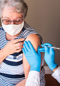 Close up of older woman getting injected with a vaccine in upper arm.