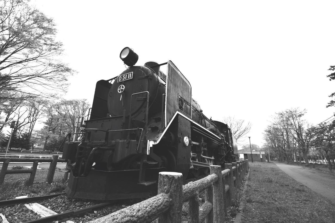 TRAIN ON RAILROAD TRACKS AGAINST CLEAR SKY