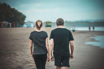 Rear view of couple walking on beach