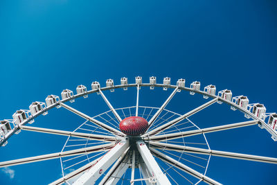 Low angle view of ferris wheel against clear blue sky