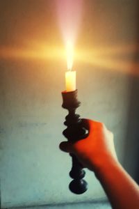 Close-up of hand holding lit candle