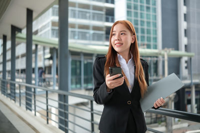 Portrait of young woman standing in city