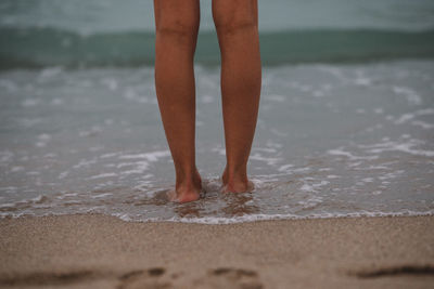 Low section of woman standing on beach