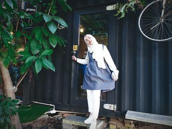 Portrait of smiling young woman standing at entrance