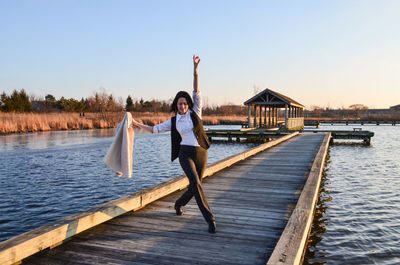 Woman dancing on pier over sea against sky