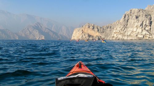 Close-up of canoe in sea by mountains against sky